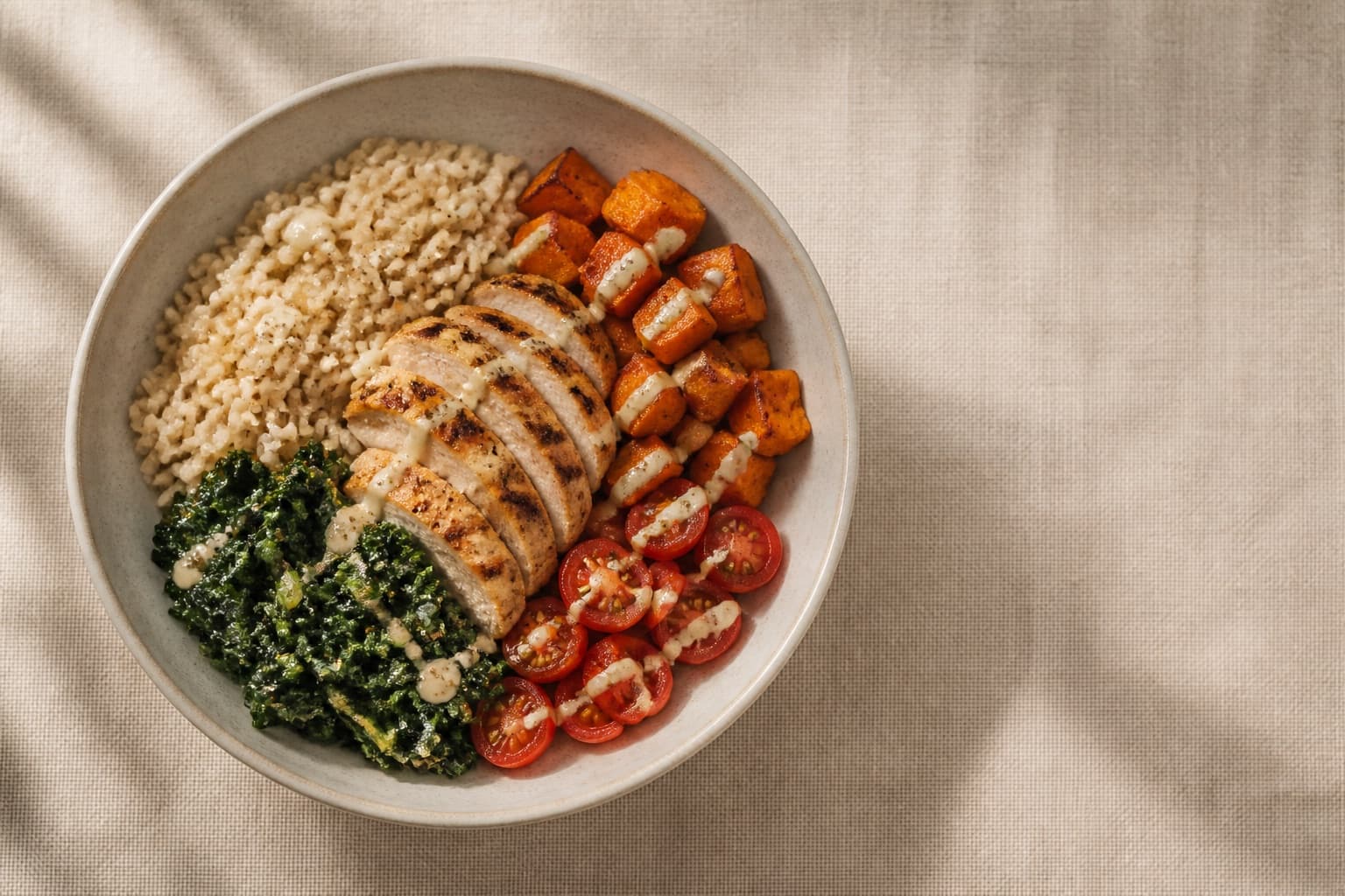 Overhead view of a grain bowl with grilled chicken, brown rice, roasted sweet potato, greens, and tomatoes. The kind of meal you can't barcode-scan or weigh.